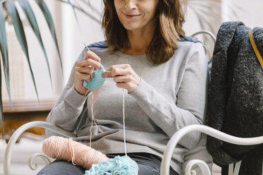 Close-up of woman sitting on chair knitting - OCAF00045