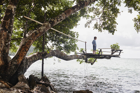 Thailand, Railay, Rai Leh East Beach, Junge auf Baumhaus über dem Meer - RORF01070