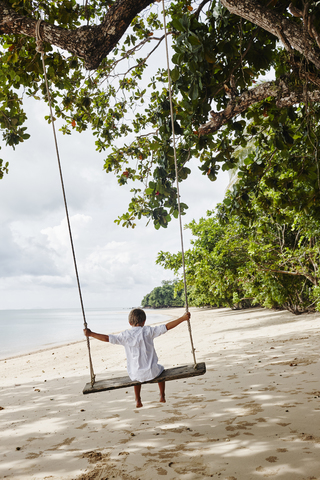 Thailand, Ko Yao Noi, Junge auf einer Schaukel am Strand, lizenzfreies Stockfoto