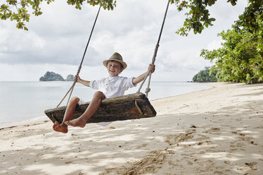 Thailand, Ko Yao Noi, glücklicher Junge auf einer Schaukel am Strand - RORF01085