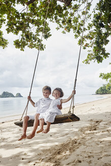 Thailand, Ko Yao Noi, glücklicher Junge und kleines Mädchen auf einer Schaukel am Strand - RORF01086