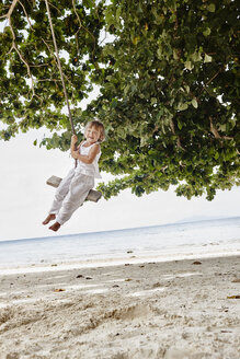 Thailand, Phi Phi Inseln, Ko Phi Phi, glückliches kleines Mädchen auf einer Seilschaukel am Strand - RORF01105