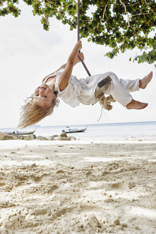 Thailand, Phi Phi Inseln, Ko Phi Phi, glückliches kleines Mädchen auf einer Seilschaukel am Strand, lizenzfreies Stockfoto