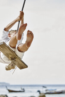 Thailand, Phi Phi Islands, Ko Phi Phi, boy on a rope swing on the beach - RORF01111