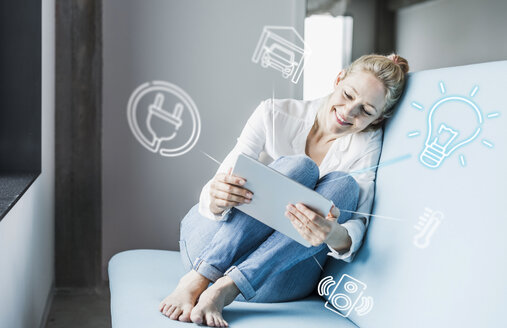 Frau sitzt im Büro und verwendet digitales Tablet zur Fernsteuerung seines intelligenten Hauses - UUF12533