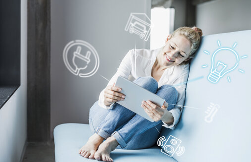 Woman sitting in office, using digital tablet to remote-control his smart home - UUF12533