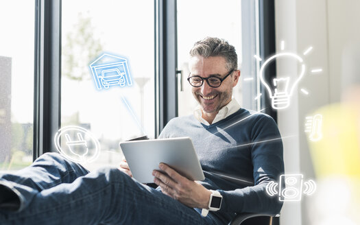 Man sitting in office, using digital tablet to remote-control his smart home - UUF12534