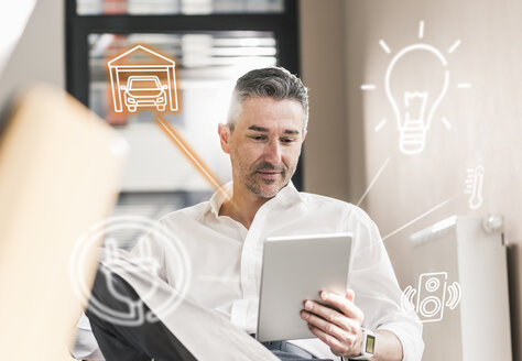 Man sitting in office, using digital tablet to remote-control his smart home - UUF12535