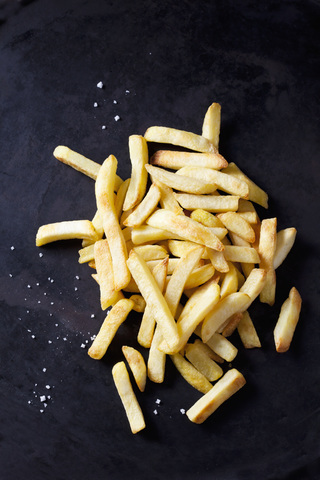 Pommes frites und Salz auf dunklem Grund, lizenzfreies Stockfoto