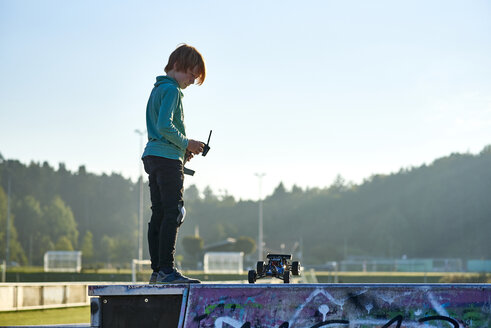Junge steht an der Wand und spielt mit einem ferngesteuerten Auto - JEDF00297