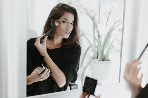 Spiegelbild einer jungen Frau beim Auftragen von Make-up - OCAF00048
