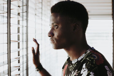 Pensive young man looking out of window - OCAF00056