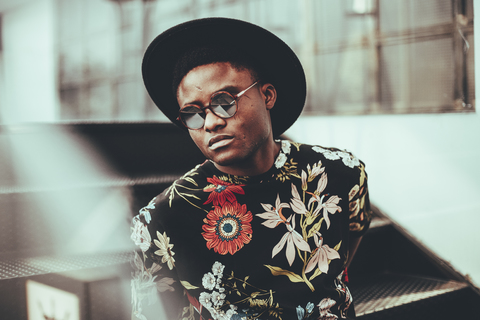 Portrait of fashionable man wearing hat, sunglasses and black t-shirt with floral design stock photo