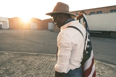 Young man wearing hat and sunglasses holding American flag - OCAF00072