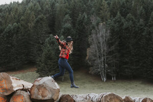Junge Frau balanciert auf Baumstämmen - OCAF00091