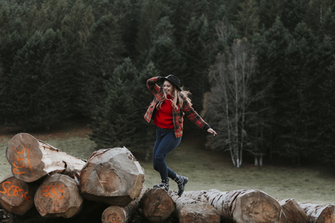 Junge Frau balanciert auf Baumstämmen, lizenzfreies Stockfoto