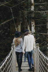 Two happy young women walking on a suspension together - OCAF00101