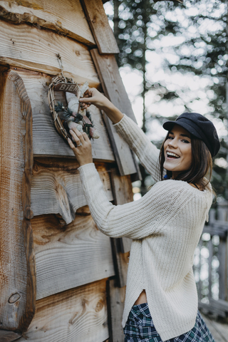 Happy young woman decorating wooden house with Christmas decoration stock photo