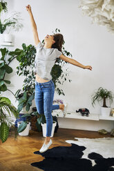 Exuberant young woman jumping in a room - BSZF00162