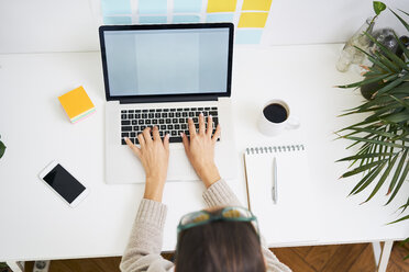 Junge Frau arbeitet am Schreibtisch mit Laptop - BSZF00163