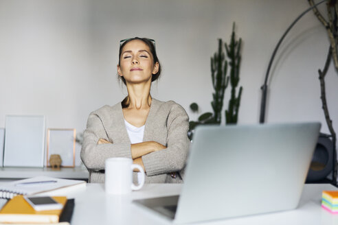 Young woman at home with laptop on desk having a break - BSZF00169