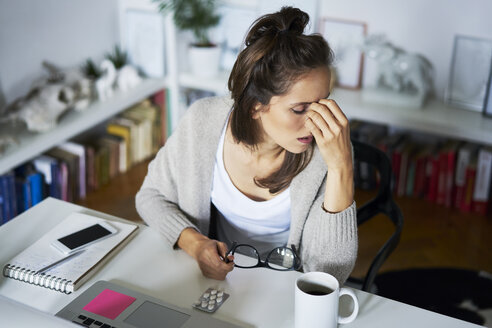 Young woman at home at desk suffering headache - BSZF00182