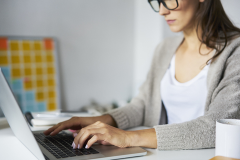 Nahaufnahme einer jungen Frau mit Laptop auf dem Schreibtisch, lizenzfreies Stockfoto