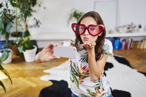 Junge Frau mit herzförmiger Brille macht Selfie - BSZF00198