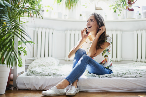Glückliche junge Frau beim Telefonieren zu Hause, lizenzfreies Stockfoto