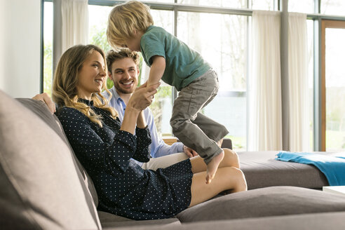 Glückliche Eltern spielen mit ihrem Sohn auf dem Sofa zu Hause - SBOF01266