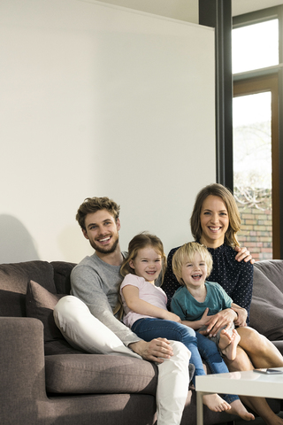 Portrait of happy family sitting on sofa at home stock photo