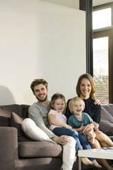 Portrait of happy family sitting on sofa at home - SBOF01300