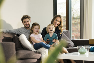 Portrait of happy family sitting on sofa at home - SBOF01301