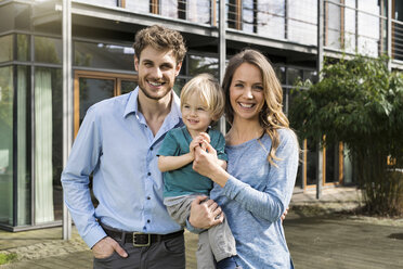 Portrait of smiling parents with son in front of their home - SBOF01311