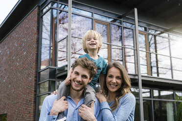 Portrait of smiling parents with son in front of their home - SBOF01312