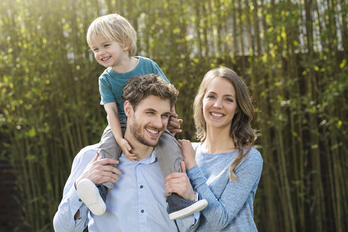 Porträt einer glücklichen Familie im Garten vor Bambuspflanzen - SBOF01321