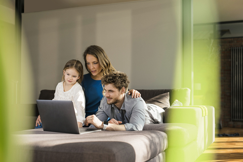 Familie benutzt Laptop auf dem Sofa zu Hause, lizenzfreies Stockfoto