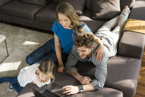 Family using laptop on sofa at home stock photo