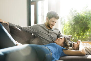 Affectionate couple smiling at each other on sofa at home - SBOF01346