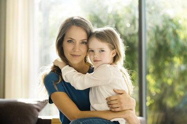 Porträt einer lächelnden Mutter, die ihre Tochter zu Hause im Arm hält - SBOF01348