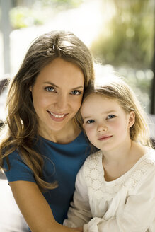 Porträt einer lächelnden Mutter mit Tochter vor einem Fenster - SBOF01349