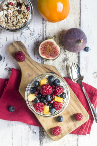 Glas Naturjoghurt mit Müsli und verschiedenen Früchten, lizenzfreies Stockfoto