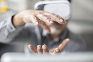 Man shaping with his hands wearing VR glasses in office - ZEF14925