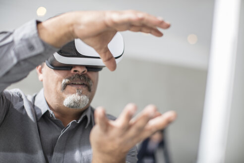 Mann, der mit seinen Händen formt und eine VR-Brille im Büro trägt - ZEF14926