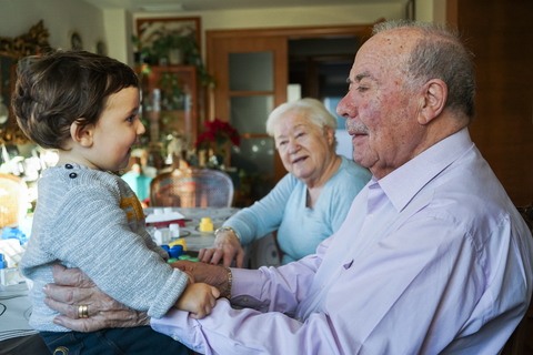 Great-grandparents playing with baby girl at home stock photo