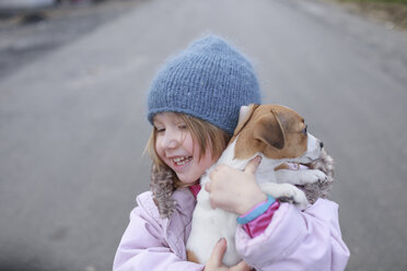 Happy little girl holding Jack Russel Terrier puppy - KMKF00144