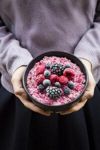 Mädchen hält Schüssel mit Overnight Oats mit gefrorenen Beeren - LVF06641