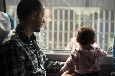 Father and baby girl traveling by train looking out of window - GEMF01870