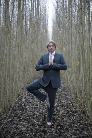 Businessman practicing yoga amidst willows stock photo