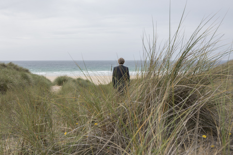 UK, Cornwall, Hayle, Geschäftsmann steht in den Stranddünen und betrachtet die Aussicht, lizenzfreies Stockfoto